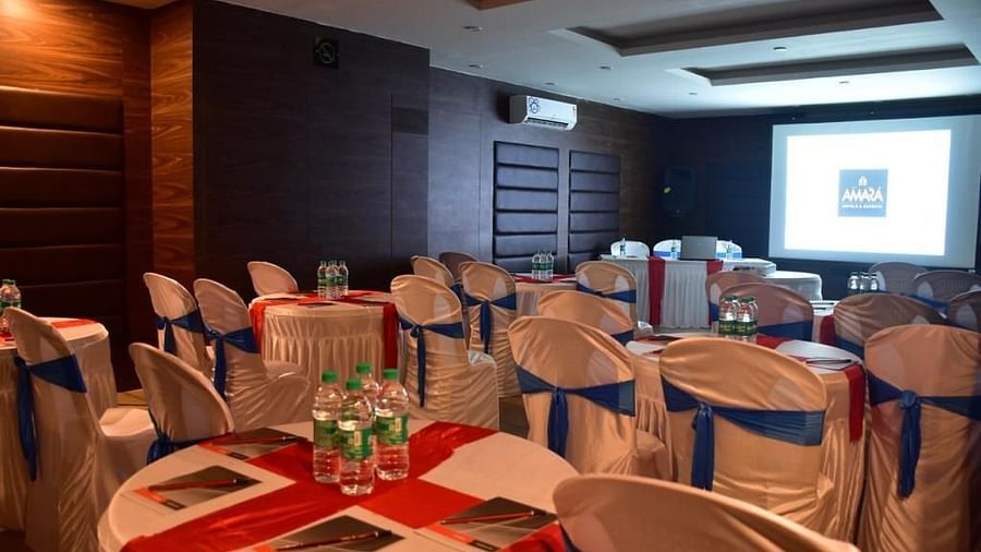 Back view of a hall with round tables and chairs facing a projector at Calux Grand Baga.