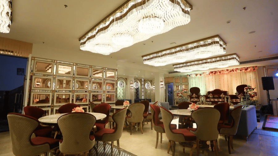A dining setup with multiples round tables and chairs around them under a ornately decorated ceiling.