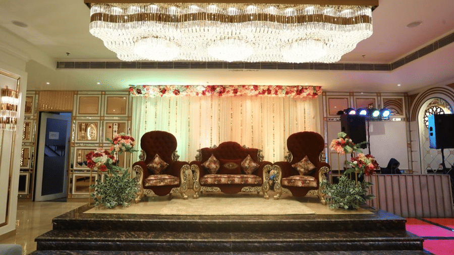 A wedding venue setup with two ornate looking chairs set up on a stage with other decorations on the side.