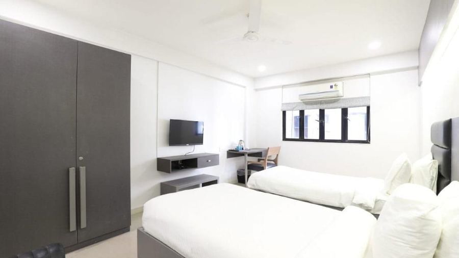Corner view shot of the Premium Twin Room at Pravasa Ahmedabad featuring bright and minimalist interiors along with a wardrobe in the corner.