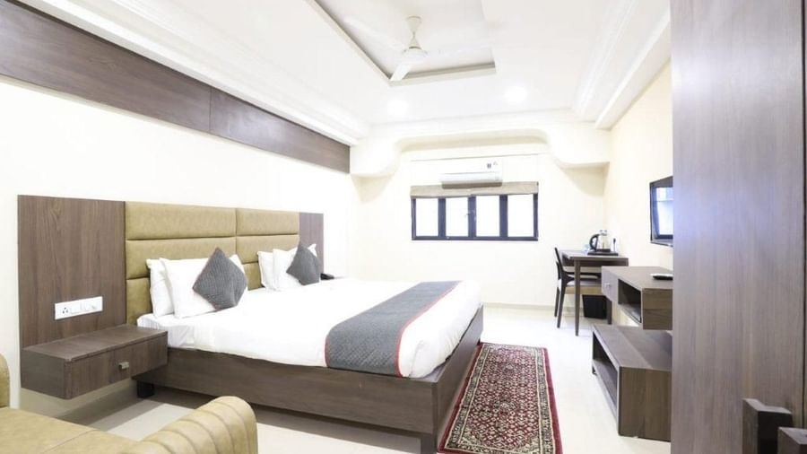 Side view of the Premium Room with bright lighting at Pravasa Stay, Ahmedabad (Alba Premier) featuring a 4-panelled window at the far end of the room. 