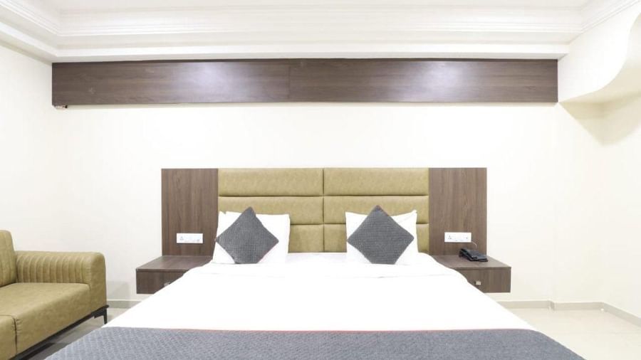 Front view of the double bed with a grey-coloured bed runner spread over it in the Premium Room of Pravasa Stay, Ahmedabad (Alba Premier).