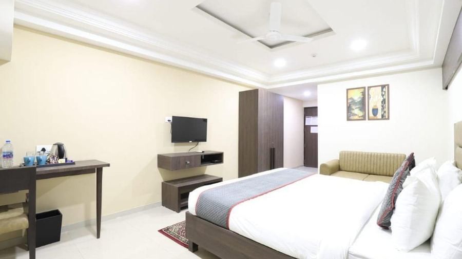 Full-view shot of the Premium Room at Pravasa Stay, Ahmedabad (Alba Premier), featuring a comfortable double bed along with a work desk and a wall-mounted television in front of it.