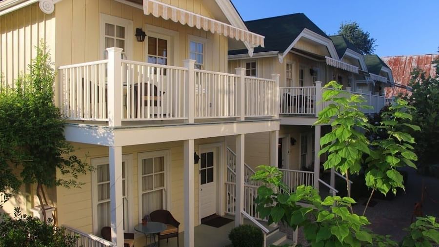 A two-storey house of Tallman Hotel with cream coloured walls and balconies depicting upper, and lower garden exterior. 