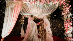 A bride and groom garlanding each other under a canopy - Karma Lakelands.