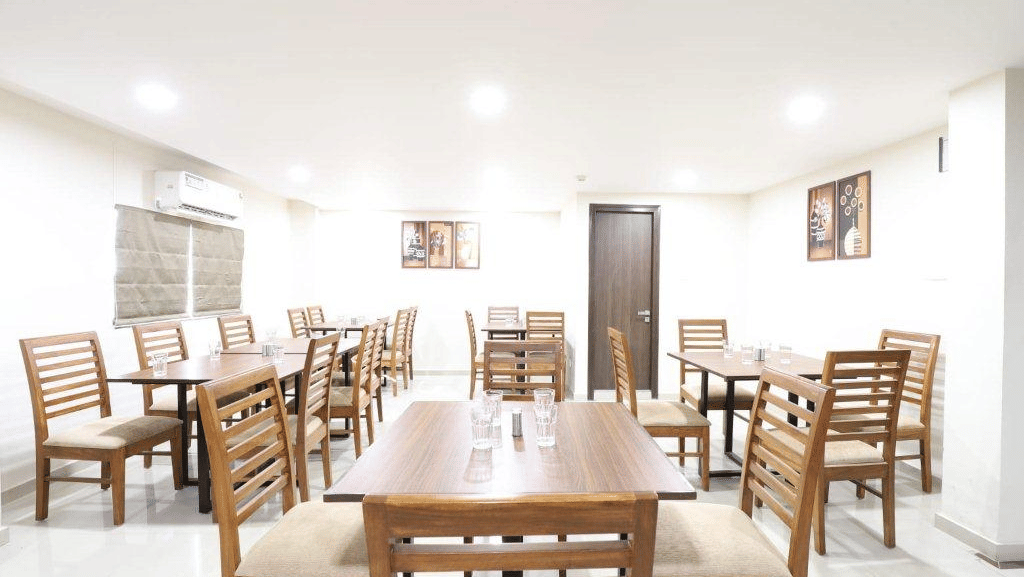 Side-angle view of a dining table with 2 chairs placed opposite to one another at Aranaya Restaurant at Pravasa Stay, Ahmedabad (Alba Premier).