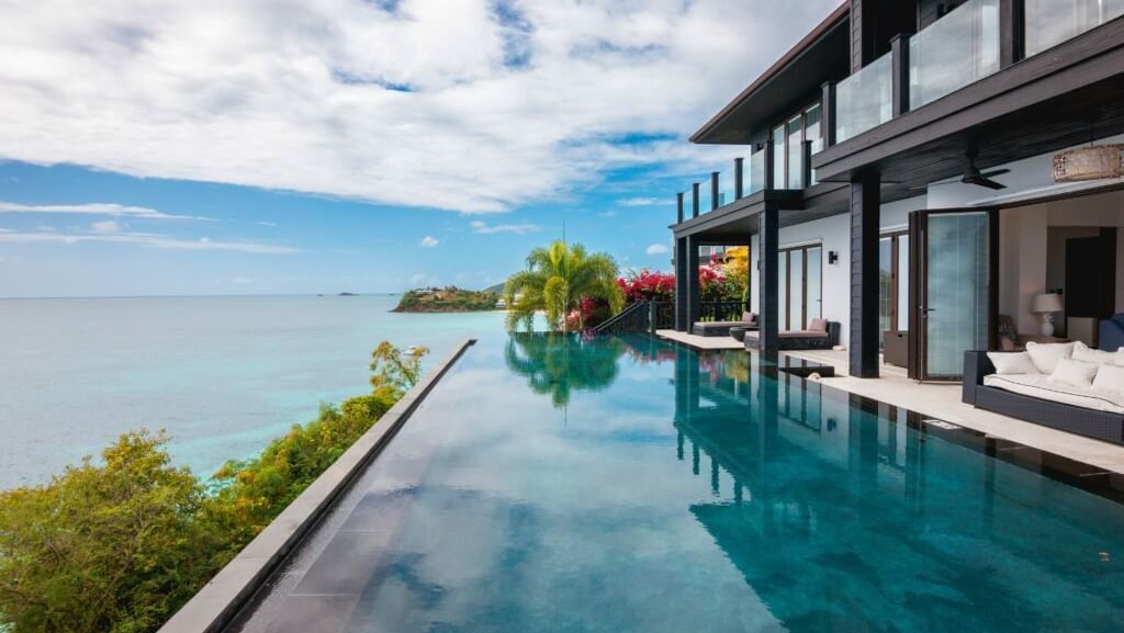 Modern infinity pool beside beachfront villa under skies at Tamarind Hills Antigua – Resort & Villas