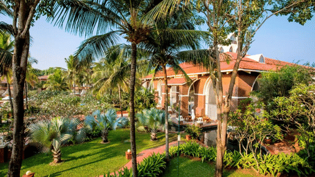 An overview of Caravela Beach Resort Goa with a garden and rooms in view.