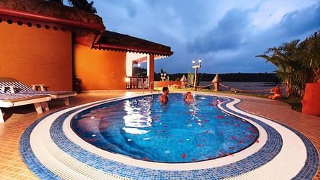 Swimming pool adjacent to the building, with decorative tiled borders around the water.