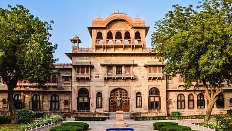 A facade image of a palace surrounded by greenery