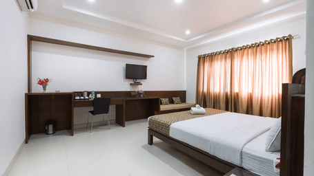 Spacious deluxe room with comfortable bed, work desk, and modern interiors at Sanctum Suites Bengaluru