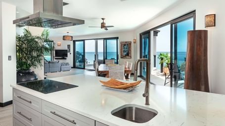 A spacious modern kitchen with a large island, stainless steel appliances, and ocean views.