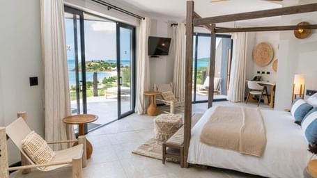 Spacious bedroom with canopy bed, seating area, and ocean view balcony at Tamarind Hills Resort and Villas - Antigua.