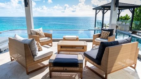 Outdoor lounge area with wicker seating overlooking the turquoise Caribbean Sea at Tamarind Hills Resorts and Villas.