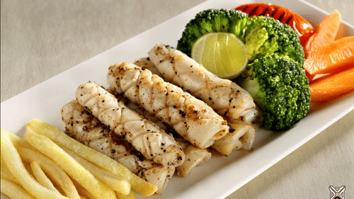 Grilled fish fillets served with golden chips, steamed broccoli, carrots, tomatoes, and a fresh lemon wedge for garnish on a plate - Abad Plaza, MG Road, Shenoy Kochi