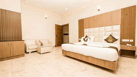 Deluxe Room With Balcony featuring a king size bed, seating area, and wooden furnishings.- Sukhi - A Luxury Stay Inn, Chikkamagaluru