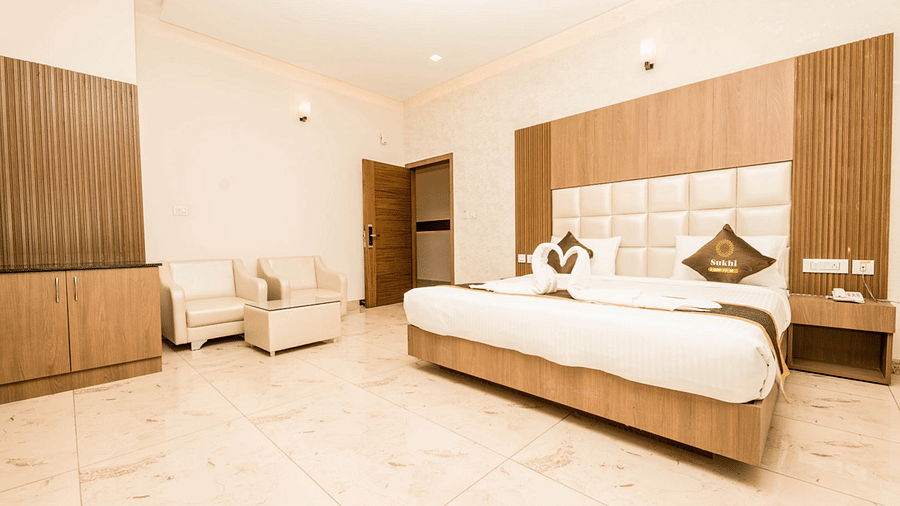 Deluxe Room With Balcony featuring a king size bed, seating area, and wooden furnishings.- Sukhi - A Luxury Stay Inn, Chikkamagaluru