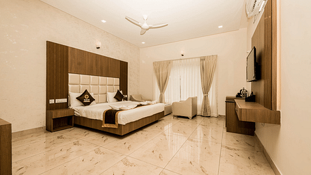 Super Deluxe Room featuring a king size bed, seating area, and a wall-mounted television.- Sukhi - A Luxury Stay Inn, Chikkamagaluru