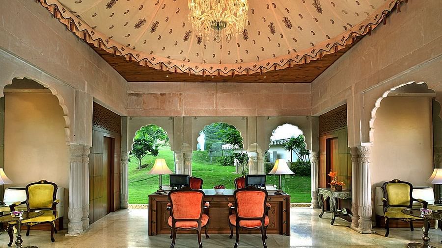 Image of the lobby at Rajasthali Resort & Spa Jaipur with chairs, tables, and a chandelier hanging from the ceiling.