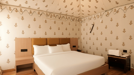 A room at Grassfield Riviera Resort, featuring a large bed, bedspreads, pillows, and a table.