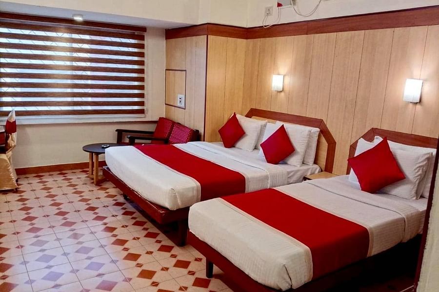 Room with a single bed, a double bed, and a seating area at Hotel Swagath, Bangalore