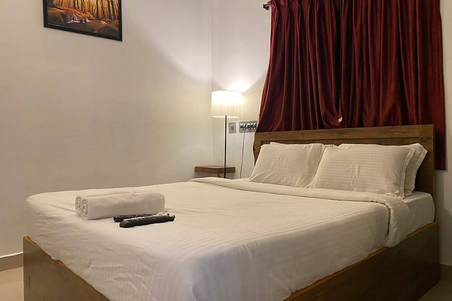 alt-text A side view of a bed with bedding in a room with a wall frame and bed lamp