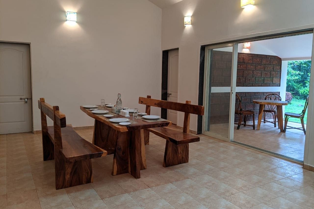 Indoor dining space with rustic wooden furniture and bright lighting at The Conservancy Bungalow.
