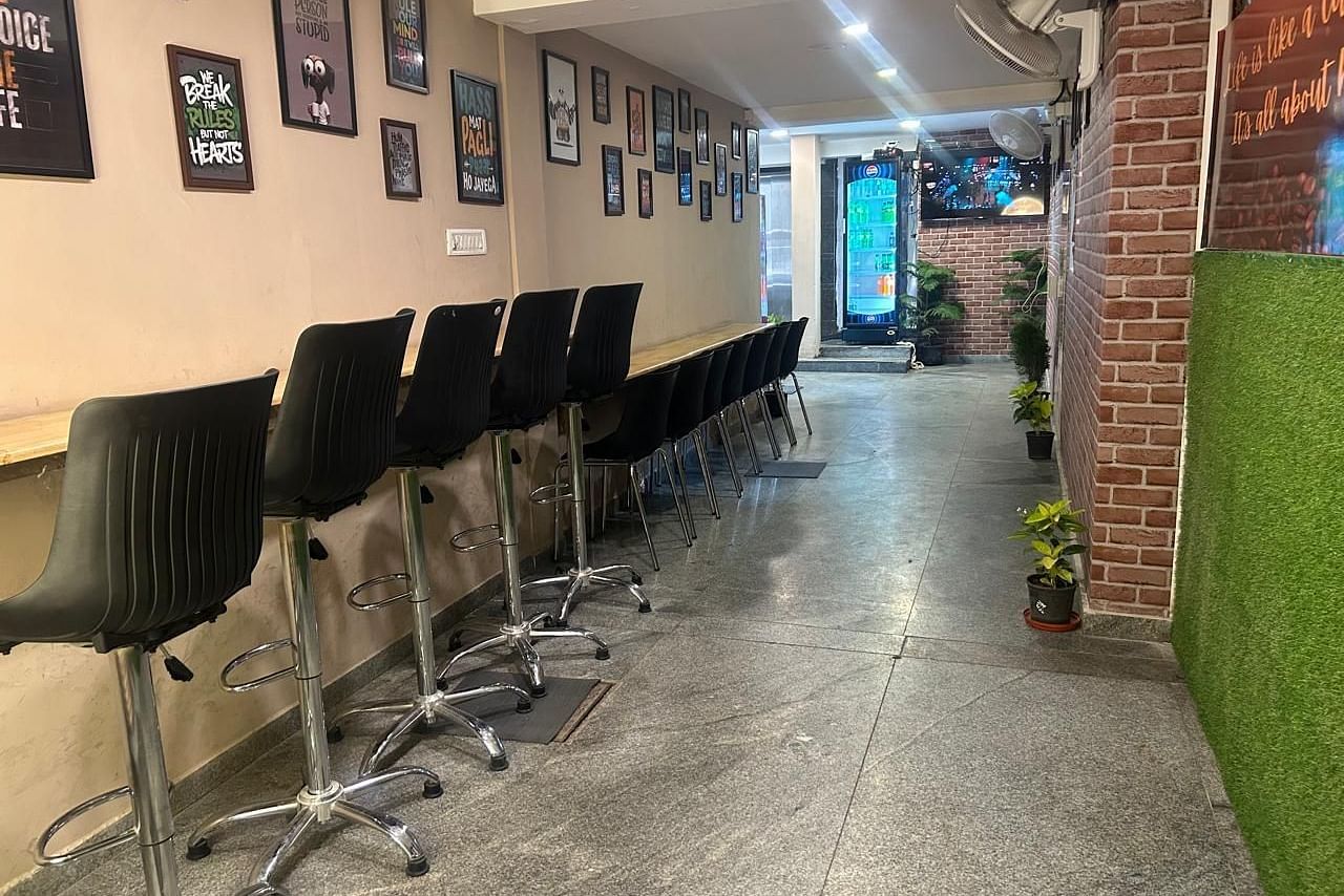A longer view of the hallway at The OnTime Hotel, Bangalore, with office-style chairs and a plant.