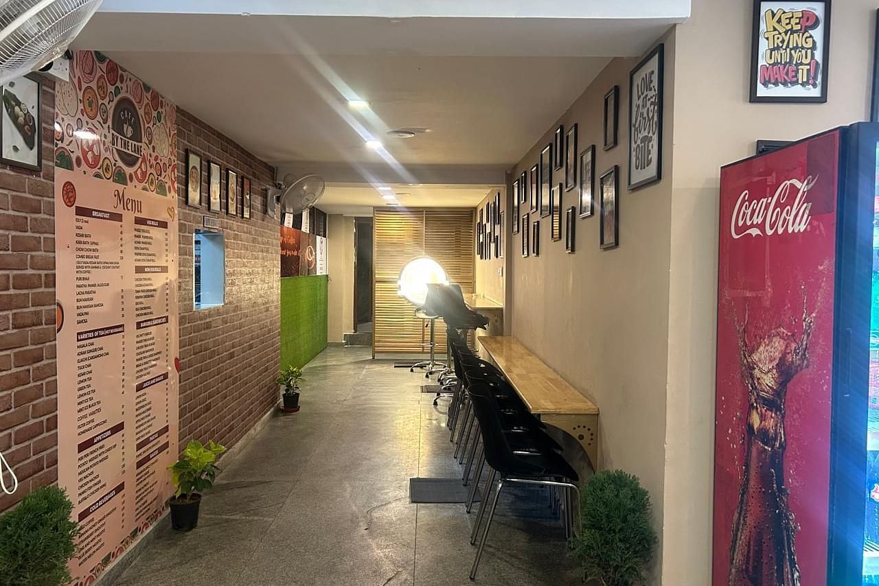 Another view down the hallway at The OnTime Hotel, Bangalore, showing a red Coca-Cola vending machine and framed pictures.