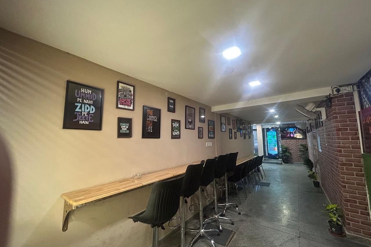 A hallway at The OnTime Hotel, Bangalore, with a long table, chairs, and framed pictures on the wall.