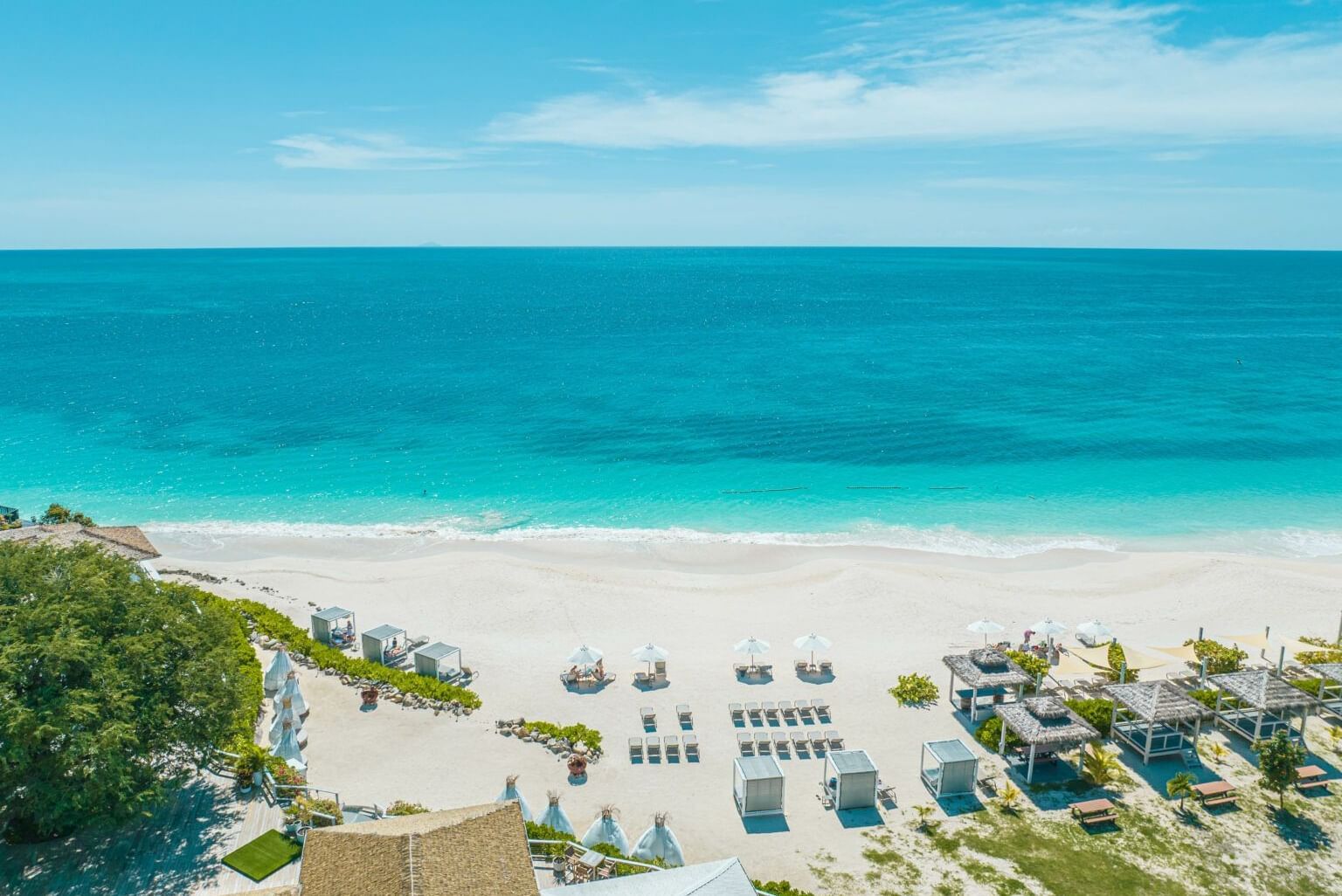Aerial view of the white sand beach and turquoise waters at Tamarind Hills Antigua – Resort & Villas