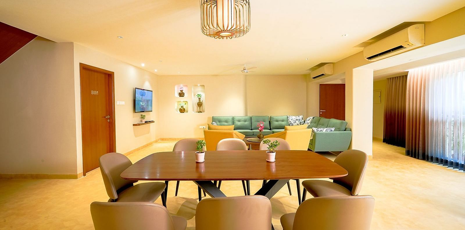 Modern dining area at Vasundhara Villa featuring a large dining table, ambient lighting, and family-friendly space.