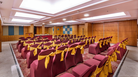 a banquet hall with theatre style seating arrangement with wood-panelled walls and ceiling lights at Libra Lords Inn Jaipur