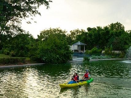 Two people paddling a yellow kayak in a calm lake surrounded by trees.