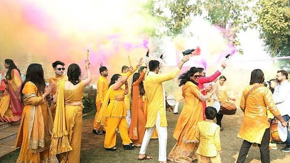 Guests joyfully dance amidst vibrant coloured smoke, creating a lively celebration at Tisya Farms, Gurgaon.