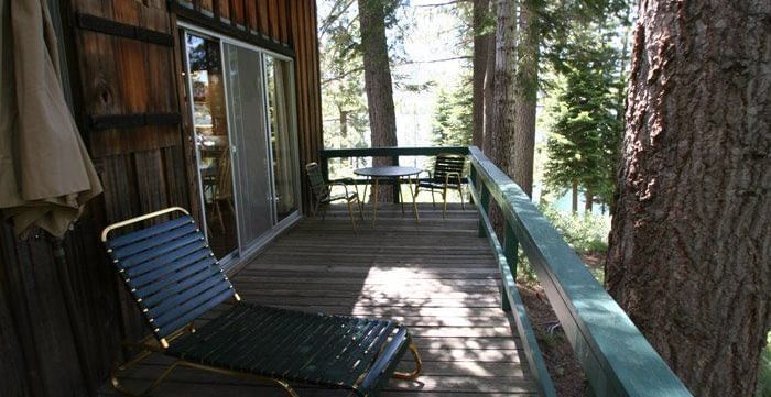 A rustic cabin deck with railings featuring a  lounge chair. - Kit Carson Lodge