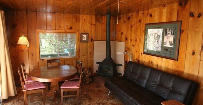 A rustic cabin interior with a round dining table, cushioned chairs and a sofa. - Kit Carson Lodge