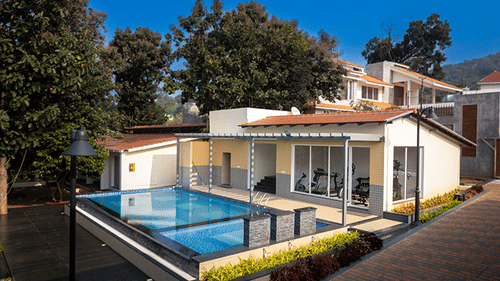 Modern villa with a private swimming pool surrounded by trees.