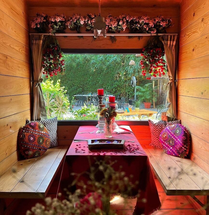 Window-side wooden seating area with red decor and flower vases at Karma Chalets.