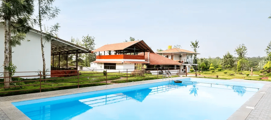 Outdoor swimming pool at Hatti Eden Coorg resort with villa and garden view