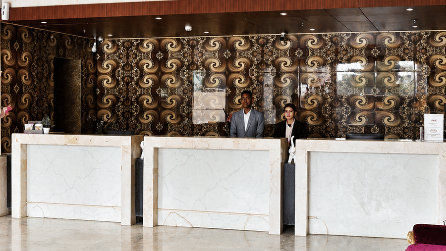 Hotel lobby at Golden Tulip Kukas Jaipur with marble flooring, white reception counter, decorative purple chairs, and warm ceiling lighting