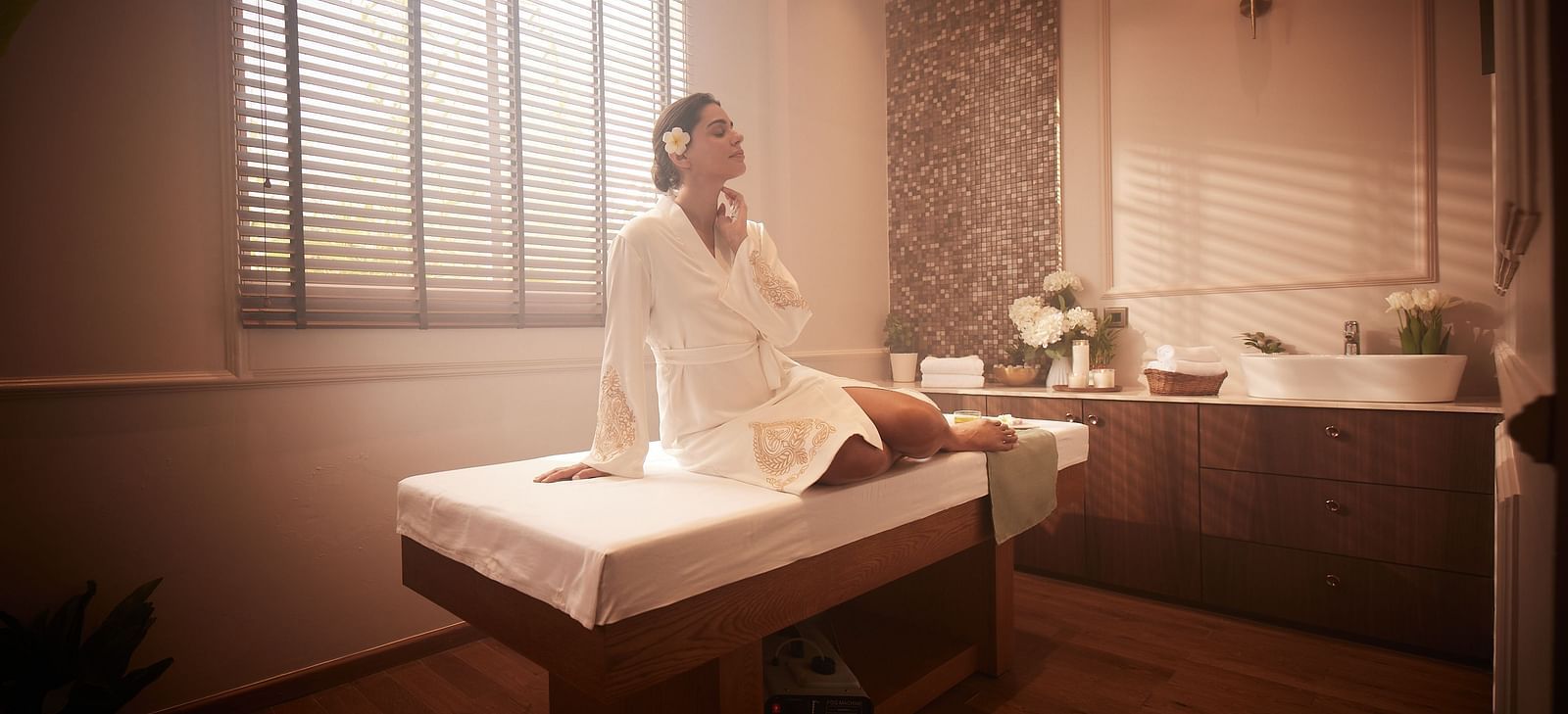 A woman sitting in an upright position on a spa bed with natural light coming from the window behind her at Imperial Goa.