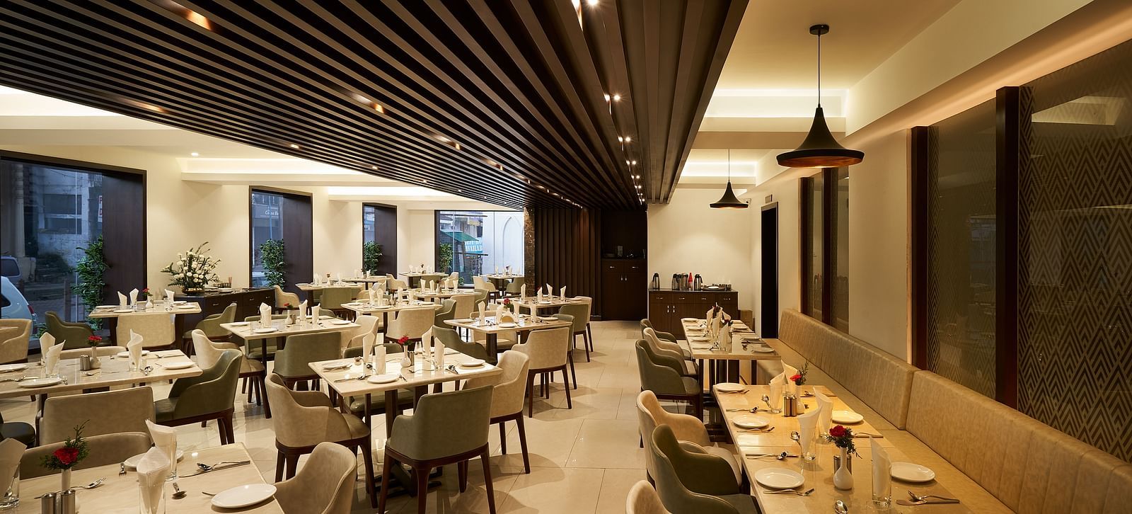 Spacious dining area with tables and chairs on one side, and seats along the wall on the other at The Hamuse Hotel, Kodaikanal.