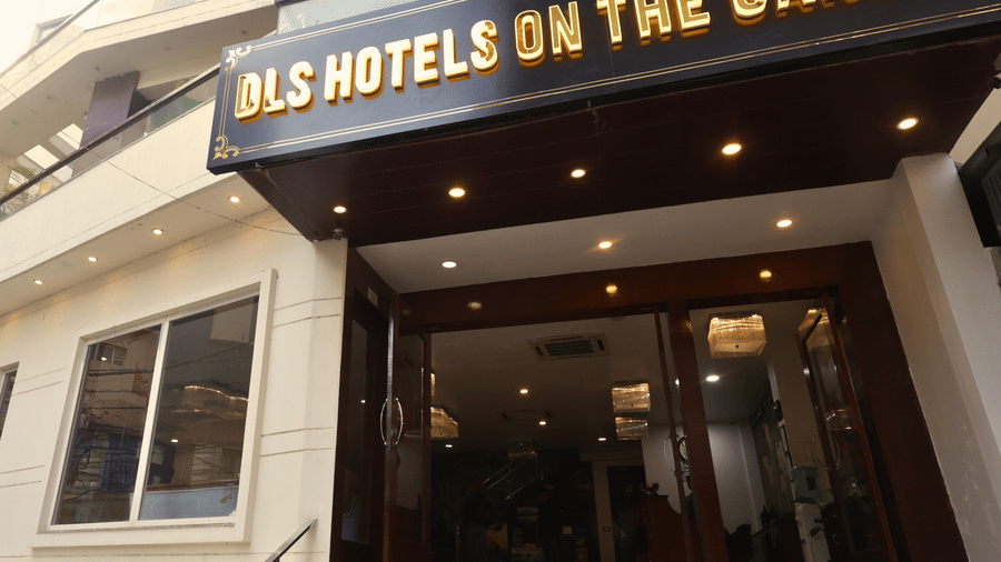 Close-up of the main entrance to DLS Hotels on the Ganges, featuring a clean staircase, glass doors, and the bright yellow hotel signage above, capturing the welcoming façade and ease of access for arriving guests.