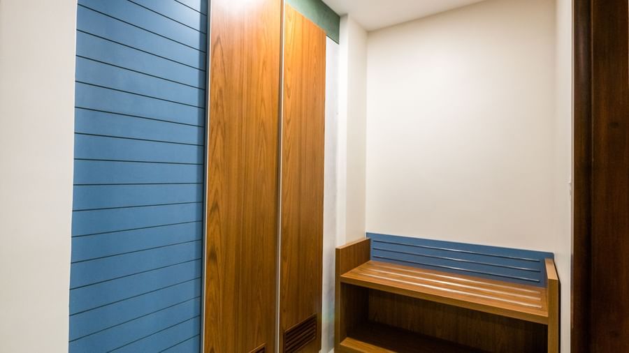 A well arranged hotel room nook with a wooden cupboard and a small seating bench, offering storage at Shilton Dee Cee.