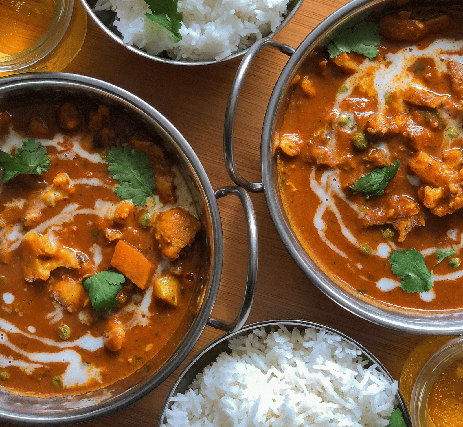 An overhead view of bowls containing white rice garnished with coriander and bowls of curry.