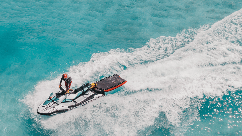 An aerial view of a person jet skiing in the turquoise waters during their Corbyn’s Cove Beach Activities