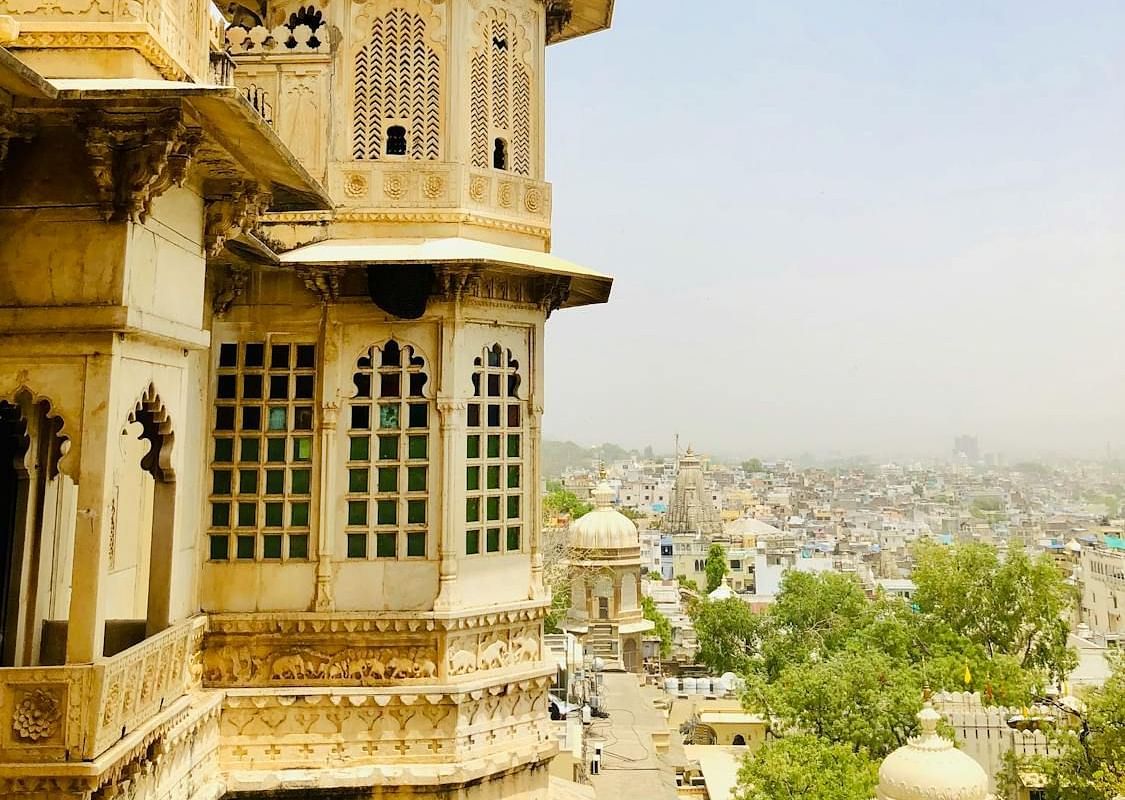 A portion of a palace with a domed tower overlooks a cityscape in the distance.