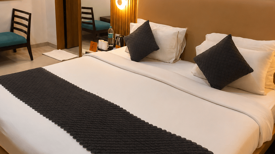 TGI Apple Inn, Ajmer Road, Jaipur | A room with a large bed, pillows, spreads, lamps, a wall art, and a table with necessities.