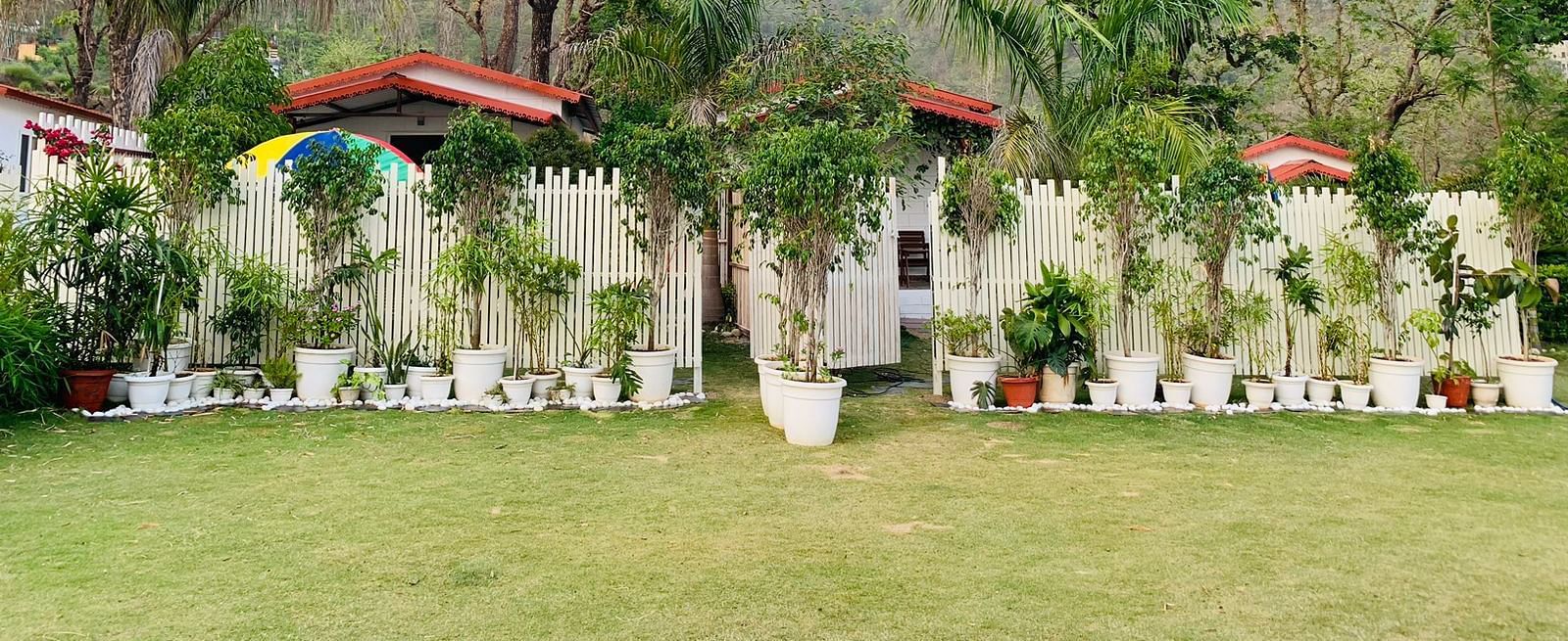 a view of the garden with manicured grass and potted plants next to the compound - Neer ganga Resorts